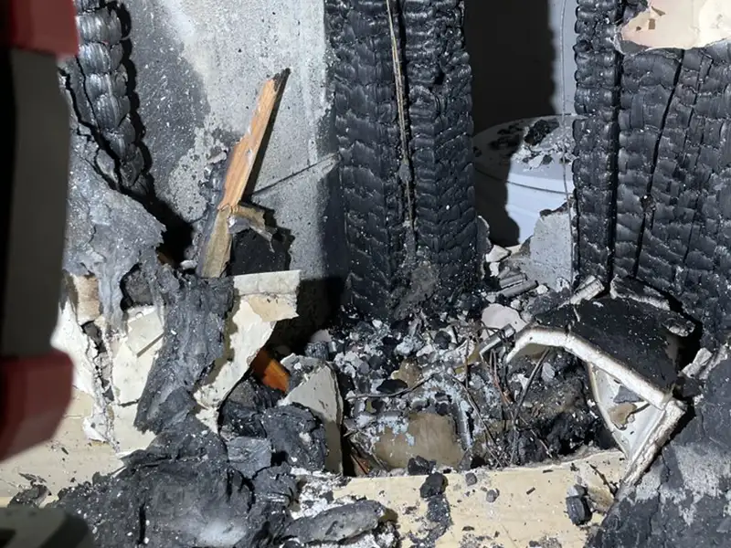 Charred wooden beams and debris inside a fire-damaged structure.